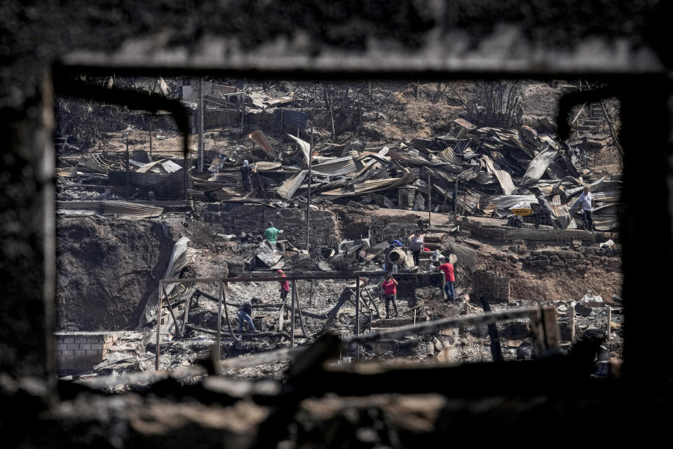 People clean up amid the rubble of homes burned by deadly forest fires in Vina del Mar, Chile, Monday, Feb. 5, 2024. (AP Photo/Esteban Felix)