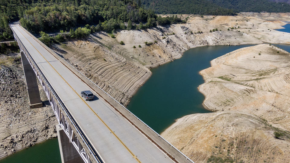 A car crosses Enterprise Bridge over Lake Oroville's dry banks Sunday, May 23, 2021, in Oroville, Calif. At the time of this photo, the reservoir was at 39 percent of capacity and 46 percent of its historical average. California officials say the drought gripping the U.S. West is so severe it could cause one of the state's most important reservoirs to reach historic lows by late August, closing most boat ramps and shutting down a hydroelectric power plant during the peak demand of the hottest part of the summer. (AP Photo/Noah Berger)