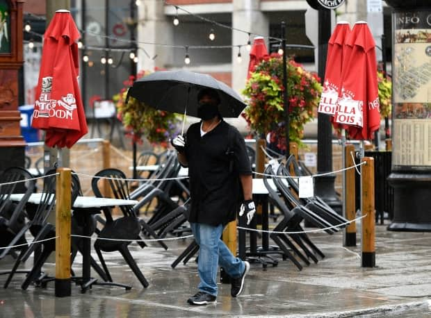 A person passes beside a Byward Market restaurant's empty patio as rain falls on Sunday, Sept. 13, 2020.  (Justin Tang/Canadian Press - image credit)