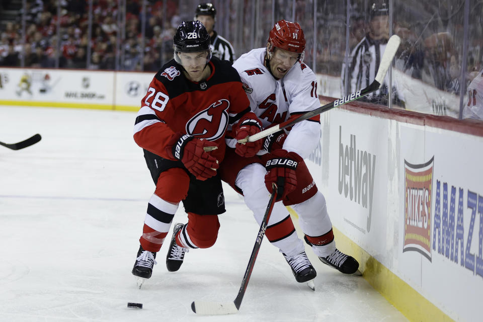 New Jersey Devils defenseman Damon Severson (28) checks Carolina Hurricanes center Jordan Staal off the puck during the first period of a NHL hockey game, Sunday, March 12, 2023, in Newark, N.J. (AP Photo/Adam Hunger)