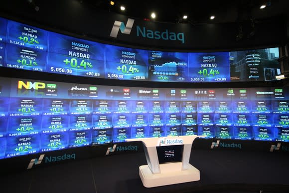 A television studio inside the Nasdaq stock exchange, with the big board of quotes in the background.