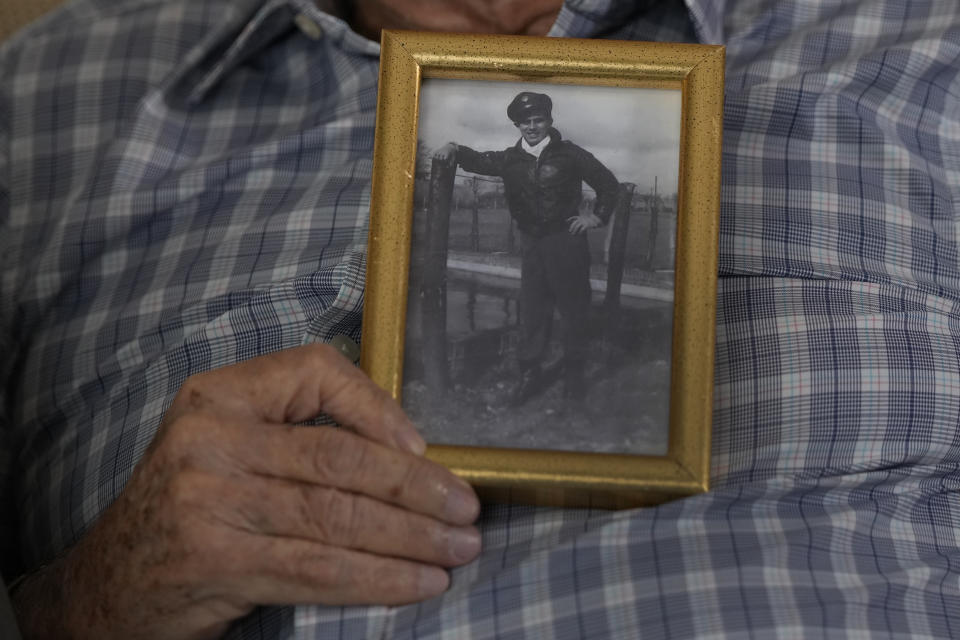 World War II veteran Harold Terens, 100, holds a photo of himself during the war when he was 20-years-old, Thursday, Feb. 29, 2024, in Boca Raton, Fla. Terens will be honored by France as part of the country's 80th anniversary celebration of D-Day. In addition, he will marry Jeanne Swerlin, 96, on June 8 at a chapel near the beaches where U.S. forces landed. (AP Photo/Wilfredo Lee)