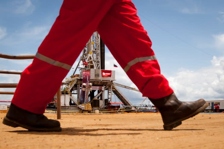 An oil worker walks past a drilling rig at an oil well operated by Venezuela's state oil company PDVSA in Morichal July 28, 2011. (Reuters)