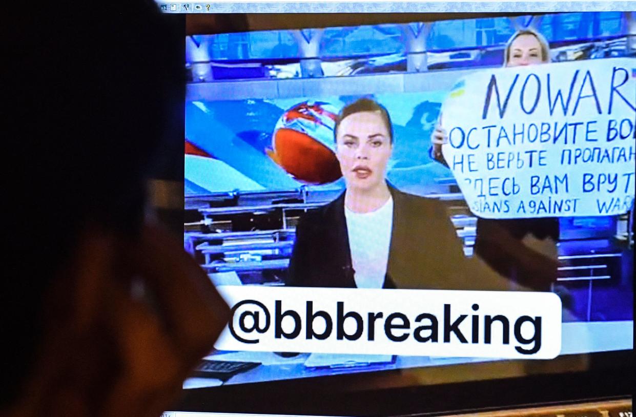 A man looks at a computer screen watching a dissenting Russian Channel One employee entering Ostankino on-air TV studio during Russia's most-watched evening news broadcast, holding up a poster which reads as 