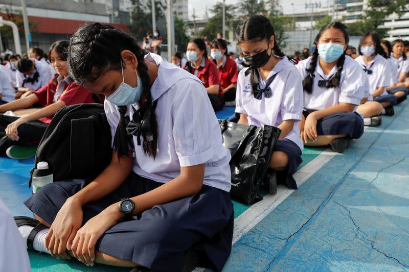 Girls wearing masks to prevent the spread of the coronavirus disease (COVID-19) sit down in the schoolyard before the start of their lesson day in Bangkok