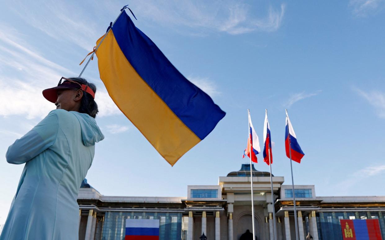 A demonstrator holds a Ukrainian flag outside the Government Palace in Ulaanbaatar to protest against Putin's visit to Mongolia