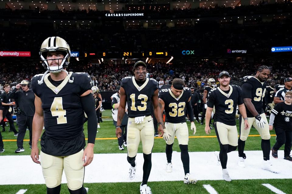 Quarterback Derek Carr, left, and wide receiver Michael Thomas, second from left, lead the Saints onto the field for their preseason opener against the Chiefs.