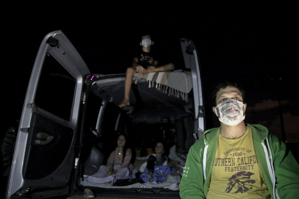 Eduardo Cavalcanti and his children watch a film at a drive-in movie theater where drivers must leave one space empty between them amid the new coronavirus pandemic in Brasilia, Brazil, Wednesday, May 13, 2020. “My kids couldn’t stand being stuck inside home anymore,” Cavalcanti said. “My wife saw the ad for the drive-in and suggested we come. It was the only option to leave home and still stay safe.” (AP Photo/Eraldo Peres)