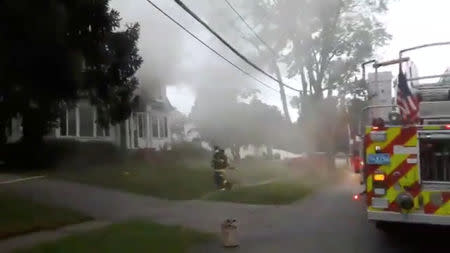 Firefighters work near a building emitting smoke after explosions in North Andover, Massachusetts, United States in this September 13, 2018 still image from social media video footage by Boston Sparks. Boston Sparks/Social Media/via REUTERS