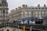 Pedestrians make their way across a sidewalk opened to foot traffic on the Pont Royal, or Royal Bridge, along grandstands used in the opening ceremonies, at the 2024 Summer Olympics, Saturday, July 27, 2024, in Paris, France. (AP Photo/Rebecca Blackwell)