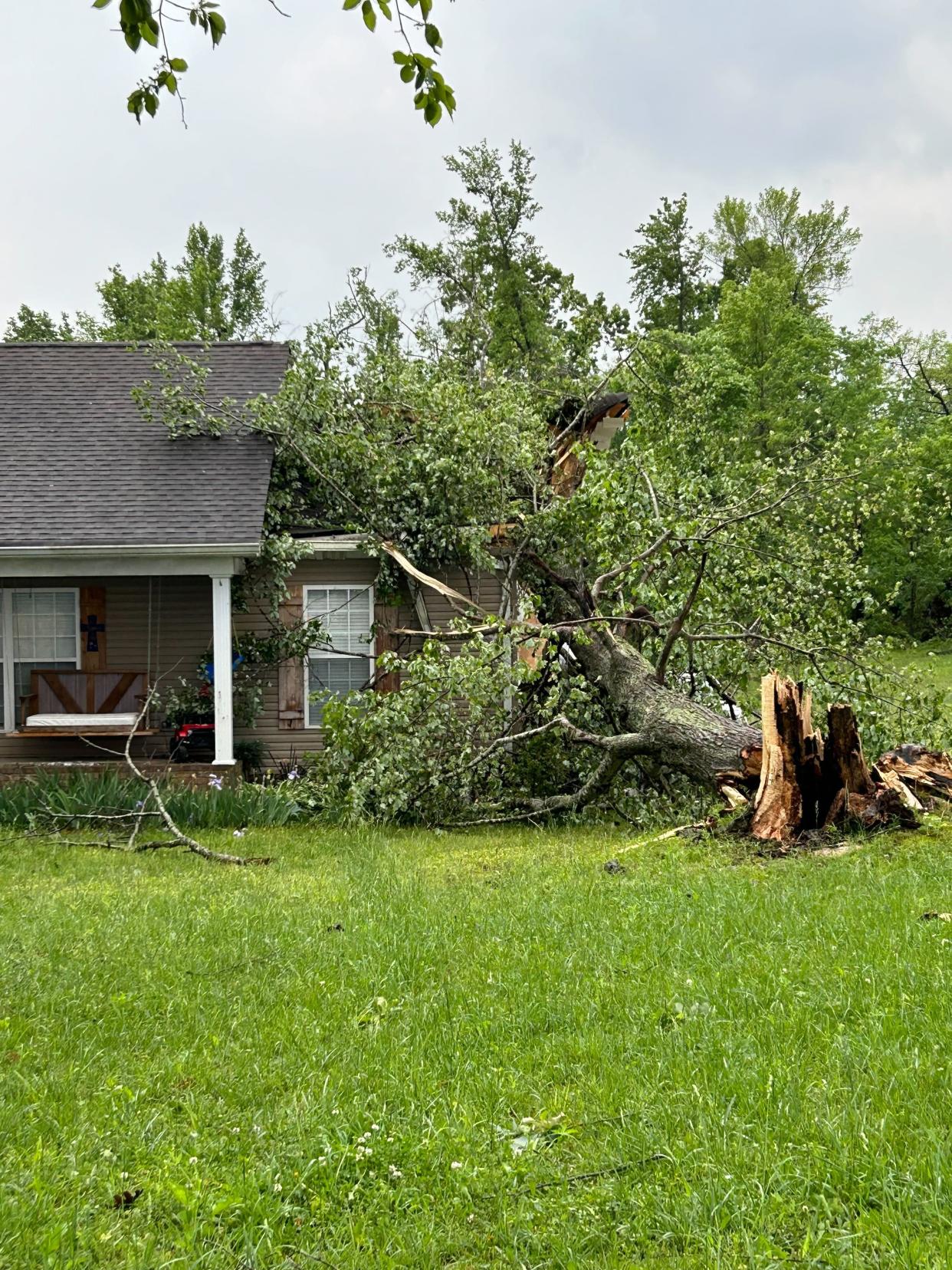 A fallen tree on a house is photographed Wednesday on the central northern border of Tennessee after a line of severe weather brought storms and a likely tornado to the area. More than 150,000 households and businesses remain without power across parts of Tennessee and North Carolina on Thursday morning, according to a USA TODAY outage tracker.