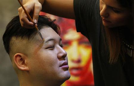 Australian Chinese Howard, 34, who does not disclose his last name, gets make-up applied before turning into a North Korean leader Kim Jong-un lookalike at a hair salon in Hong Kong November 27, 2013. REUTERS/Bobby Yip