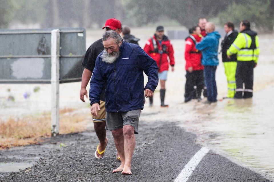 People move away from flood water in Hastings, southeast of Auckland, New Zealand (AP)