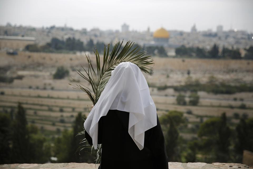 A Catholic nun holds a palm frond as she looks toward Jerusalem's Old City