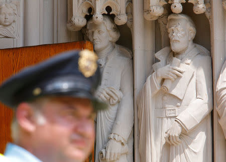 A Duke University security guard keeps watch near the defaced statue of Confederate commander General Robert E. Lee, which stands next to a statue of Thomas Jefferson, at Duke Chapel in Durham, North Carolina, U.S. on August 17, 2017. REUTERS/Jonathan Drake