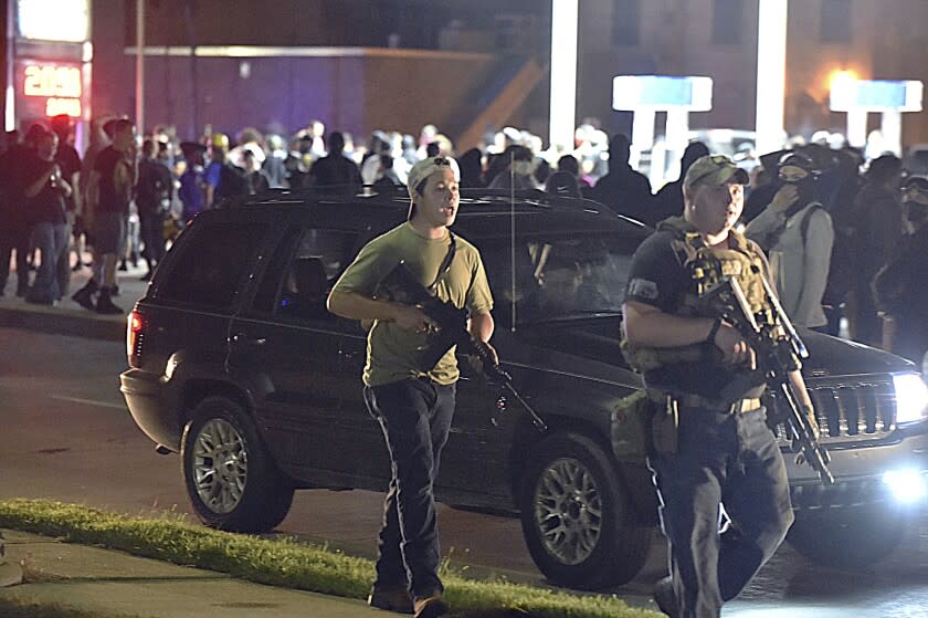 FILE - in this Aug. 25, 2020 file photo, Kyle Rittenhouse, left, with backwards cap, walks along Sheridan Road in Kenosha, Wis., with another armed civilian. Rittenhouse, the Illinois man accused of killing two people during the chaotic protests that followed the police shooting of Jacob Blake in Wisconsin, was due Friday, May 21, 2020, to make his first in-person court appearance. COVID-19 protocols in the Kenosha County courthouse have forced Rittenhouse to make all his court appearances since he was charged in August via video from his attorney's office. (Adam Rogan/The Journal Times via AP, File)