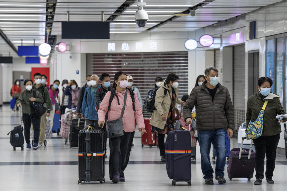 Travelers wearing face masks with their luggage head to the immigration counter at the departure hall at Lok Ma Chau station following the reopening of crossing border with mainland China, in Hong Kong, Sunday, Jan. 8, 2023. Travelers crossing between Hong Kong and mainland China, however, are still required to show a negative COVID-19 test taken within the last 48 hours, a measure China has protested when imposed by other countries. (AP Photo/Bertha Wang)