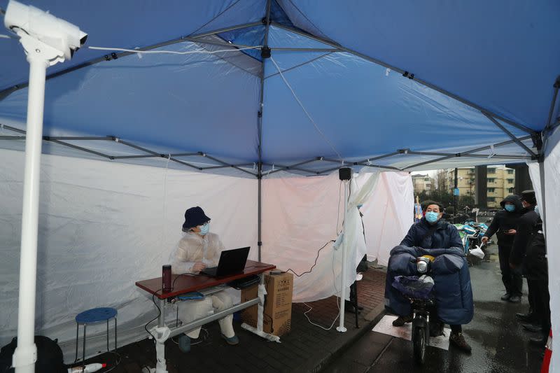 Man wearing a face mask rides his bike into a tent with an infrared imaging system to detect body temperature, at an entrance of a residential community following an outbreak of the novel coronavirus in the country, in Hangzhou