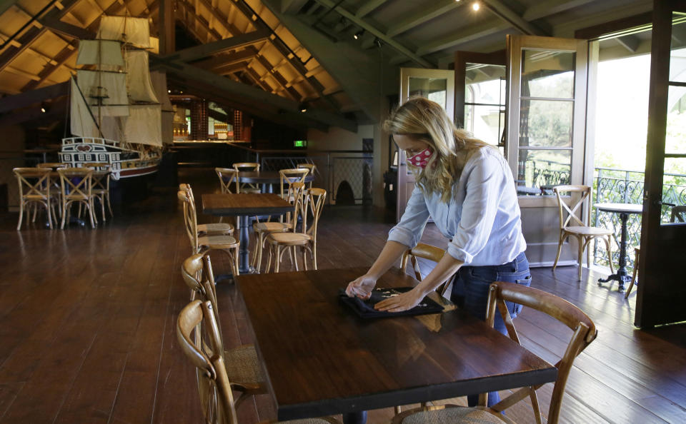 FILE - In this May 21, 2020 file photo, Lillian Fechter folds merchandise to be displayed for sale on a socially distanced table in a tasting area at the Francis Ford Coppola Winery in Geyserville, Calif. The U.S. government's small business lending program sent pandemic relief money into unexpected corners of the entertainment industry. Francis Ford Copppola, director of "The Godfather" and "Apocalypse Now," received a loan of between $5 million and $10 million that went to workers at his winery. (AP Photo/Eric Risberg, File)