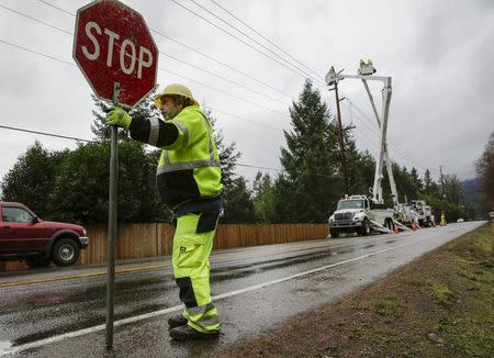 A worker directs traffic as crews work to restore power lines along Issaquah-Hobart Road Southeast in Issaquah, Washington December 10, 2015. REUTERS/Jason Redmond