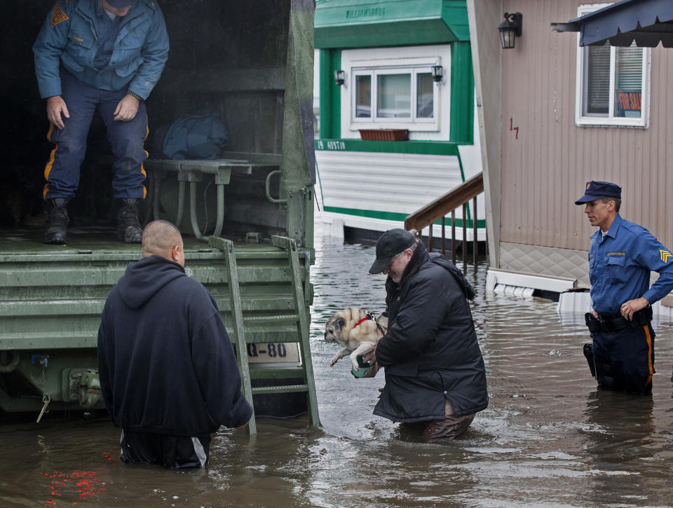 FILE - In this Oct. 30, 2012, file photo, a man walks with his dog to a National Guard vehicle after leaving his flooded home at the Metropolitan Trailer Park in Moonachie, N.J., in the wake of Superstorm Sandy. The storm drove New York and New Jersey residents from their homes, destroyed belongings and forced them to find shelter for themselves - and for their pets, said owners, who recounted tales of a dog swimming through flooded streets and extra food left behind for a tarantula no one was willing to take in. (AP Photo/Craig Ruttle, File)