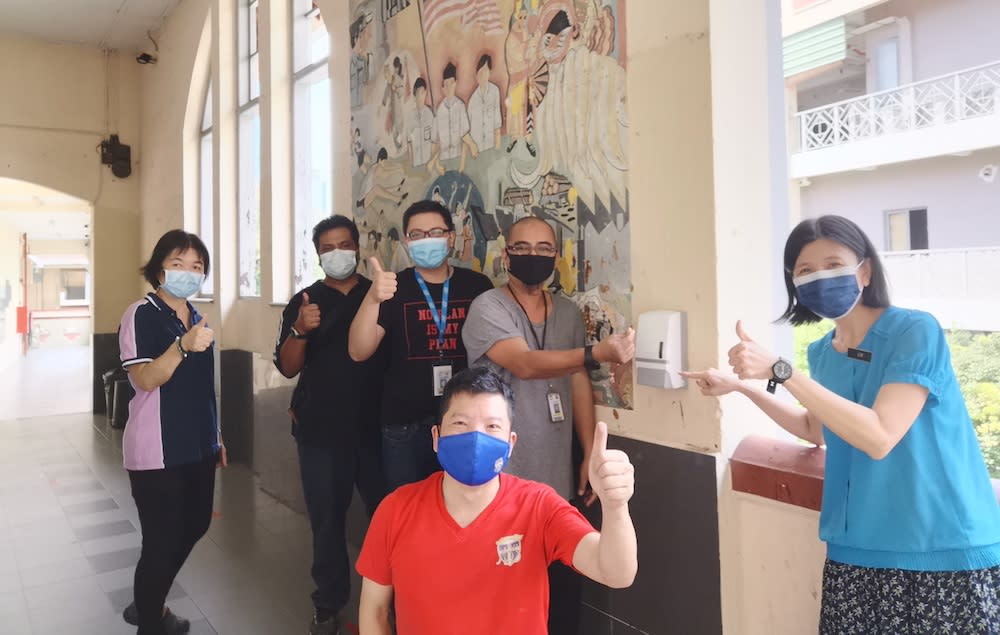 Yum and teachers from the Methodist Boys School KL posing next to the newly-installed hand sanitiser dispensers. — Picture courtesy of KC Yum.