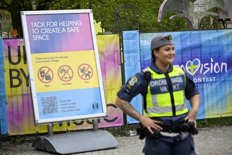 Ein Wachmann steht vor einem Informationsschild im Eurovision Dorf im Folkets Park in Malmö, Schweden, Mai 2024.