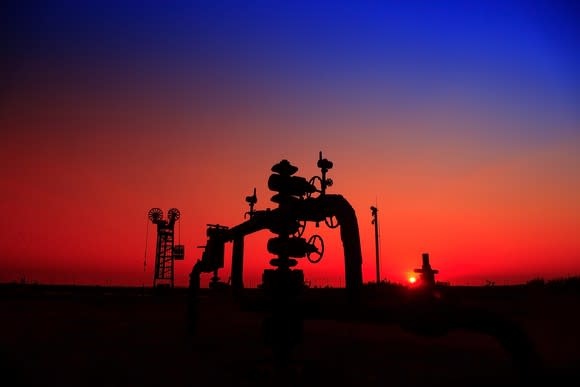 A natural gas well with pipelines at sunset.