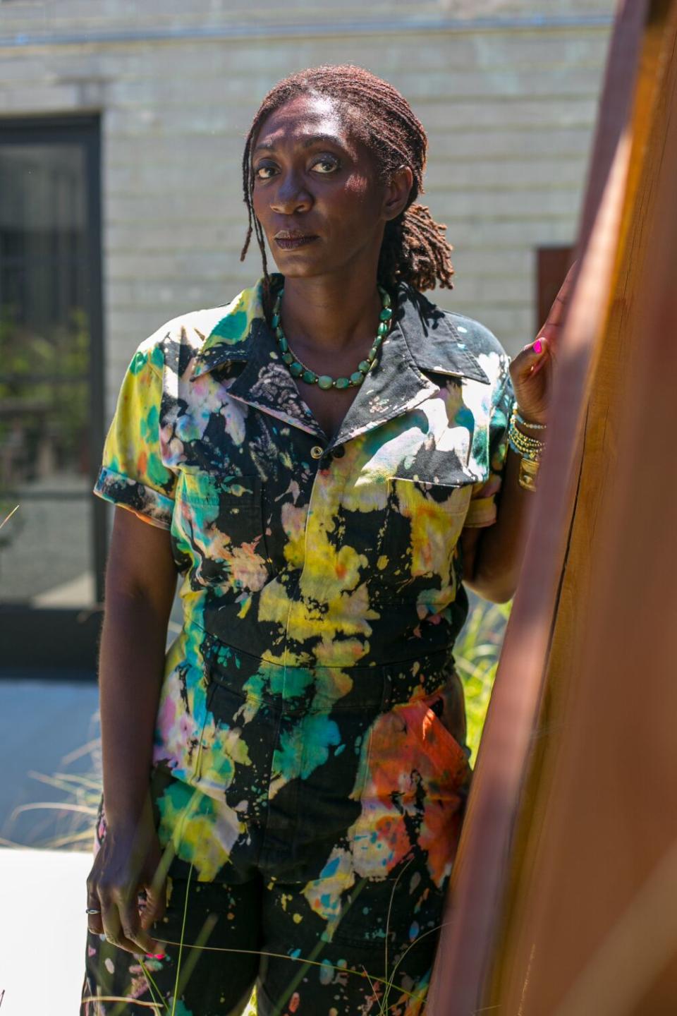 A woman in a brightly colored, patterned outfit poses for a photograph.