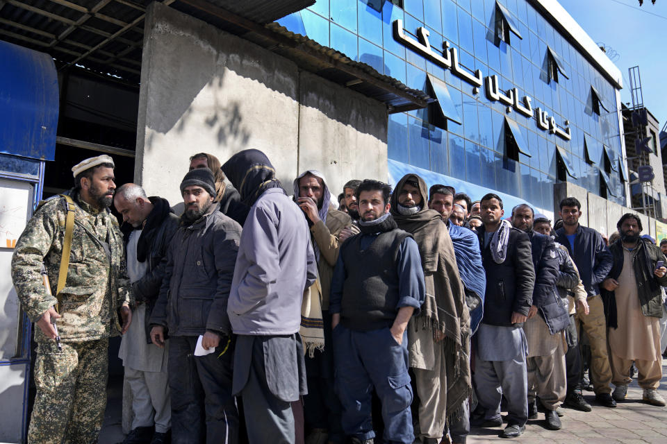 A Taliban fighter stands guard in front of people waiting to enter a bank, in Kabul, Afghanistan, Sunday, Feb. 13, 2022. During a press conference in Kabul on Sunday, former President Karzai called a White House order freeing $3.5 billion in Afghan assets for America's 9/11 families “an atrocity against the Afghan people." (AP Photo/Hussein Malla)