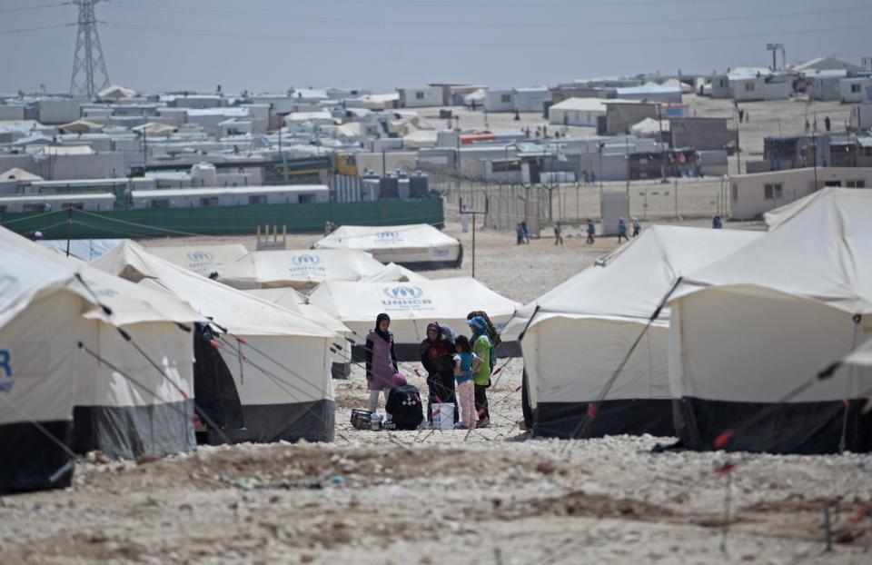 In Thursday April 17, 2014 photo, Syrian refugees wash cooking pots between their tents at Zaatari refugee camp, near the Syrian border in Jordan. Some residents, frustrated with Zaatari, have left to set up new, informal camps on open lands, to escape tensions and get closer to possible job opportunities. (AP Photo/Khalil Hamra)