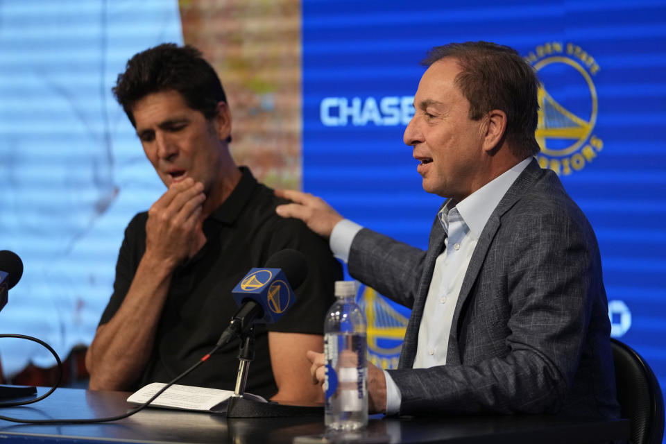 Golden State Warriors owner Joe Lacob, right, puts his hand on the shoulder of president and general manager Bob Myers during an NBA baseball news conference in San Francisco, Tuesday, May 30, 2023. Myers is departing the Warriors after building a championship team that captured four titles in an eight-year span. One of the most successful GMs over the past decade in any sport, Myers' contract was set to expire in late June. (AP Photo/Eric Risberg)