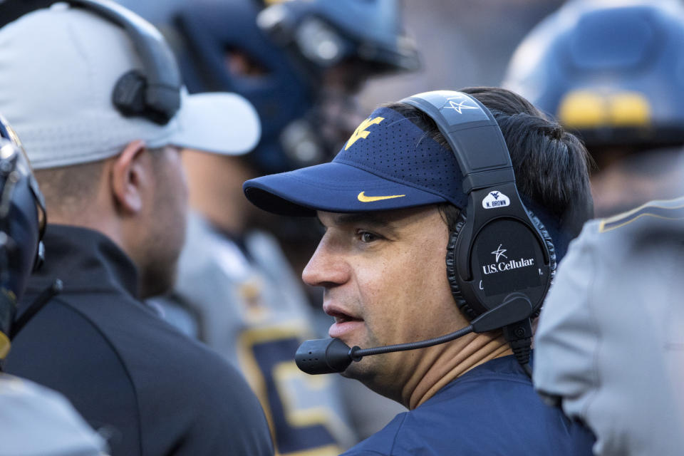 West Virginia head coach Neal Brown speaks with members of his staff during the second half of an NCAA college football game against Iowa State, Saturday, Oct. 12, 2019, in Morgantown, W.Va. (AP Photo/Raymond Thompson)