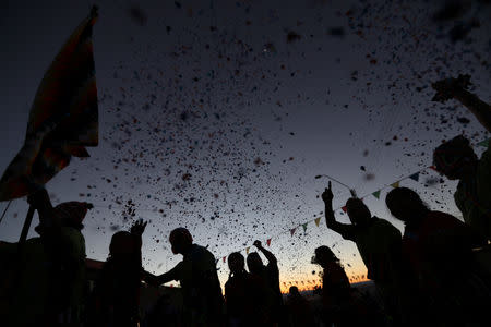 Locals dance amidst confetti at sunset during a religious holiday in the Peine area on the Atacama salt flat in the Atacama desert, Chile, August 15, 2018. REUTERS/Ivan Alvarado