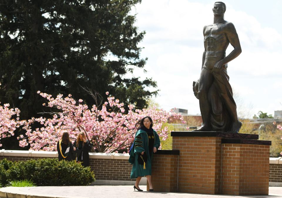 A Michigan State University Class of 2023 graduate poses for a picture in front of Sparty early Thurday afternoon, May 4, 2023.