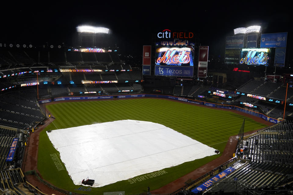 The tarp covers the field at CitiField, Monday, Oct. 3, 2022, in New York. Monday's baseball game between the New York Mets and the Washington Nationals has been postponed to Tuesday Oct. 4, 2022 at 4:10pm. (AP Photo/Frank Franklin II)