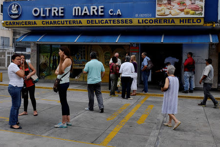 People gather outside a deli as they wait for a government-controlled special sale in Caracas, Venezuela September 14, 2018. REUTERS/Marco Bello