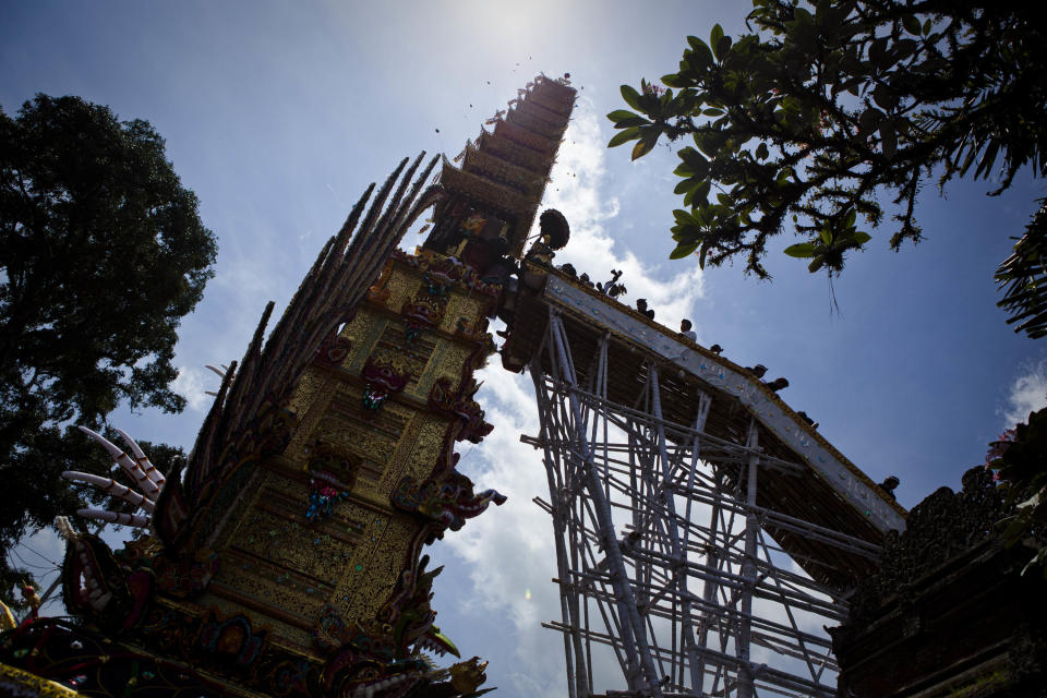 UBUD, BALI, INDONESIA - AUGUST 18: Balinese men place the coffin of Anak Agung Rai Niang in a 'bade' or cremation tower during the Hindu Royal cremation - also know as the Pengabenan - for the late Anak Agung Niang Rai, mother of Gianyar Regent, Tjokorda Oka Artha Ardana Sukawati, at Puri Ubud in Gianyar Bali on August 18, 2011 in Ubud, Bali, Indonesia. Niang Rai died in a Denpasar hospital in May; and will involve a nine level, 24m high 'bade' or body carring tower, made by upto 100 volunteers from 14 local villages. It will be carried to the cremation by 4500 Ubud residents. (Photo by Ulet Ifansasti/Getty Images)