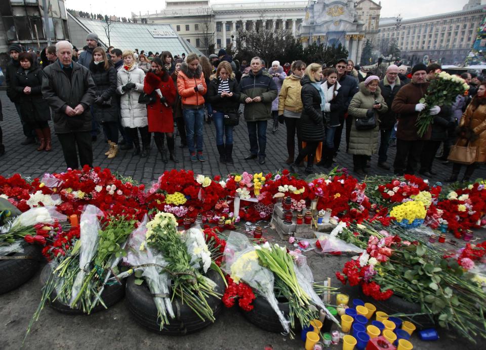 People mourn at the site where anti-Yanukovich protesters have been killed in recent clashes in Kiev