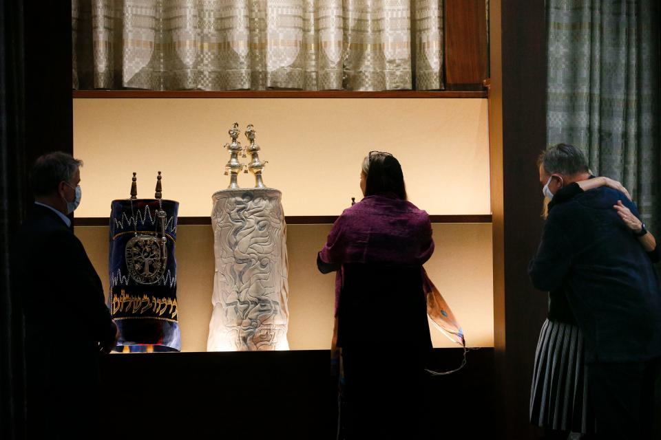 Senior Rabbi Sharon Mars, center, places the last of three Torah scrolls into the ark at Temple Israel's new home near Bexley while Harriette Hansel, of the building committee, hugs fellow congregation member Bob Keiden during grand opening ceremonies on Sunday.