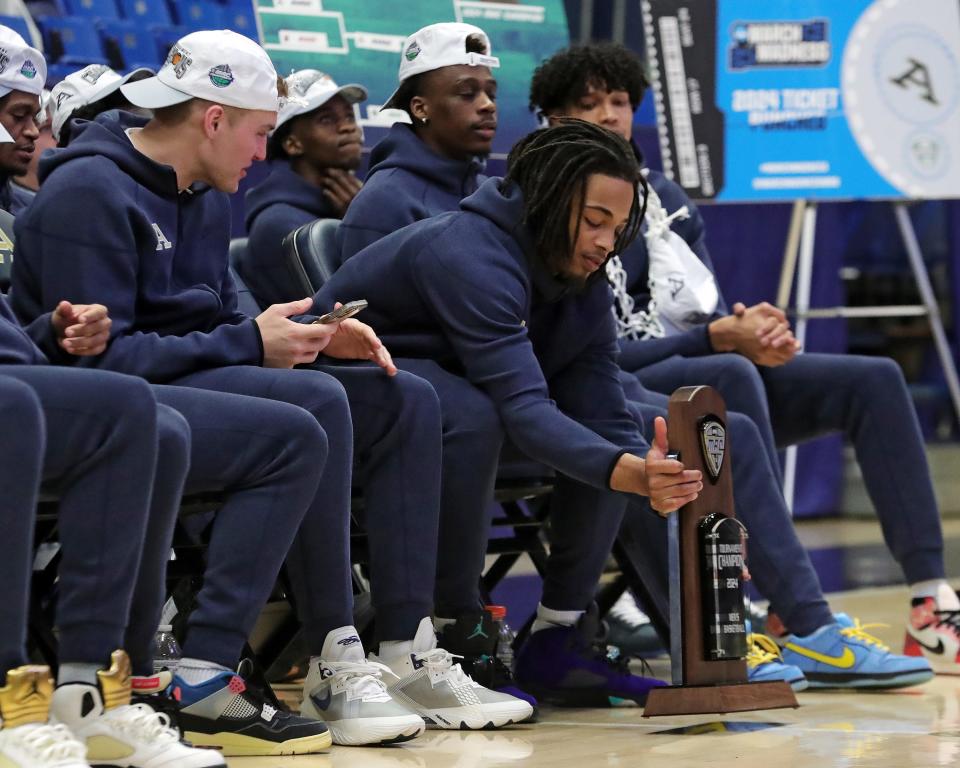 Akron guard Greg Tribble sets the MAC Tournament championship trophy down before the start of a watch party Sunday.