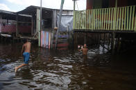Children play on a street flooded by the rise of the Negro river in Iranduba, Amazonas state, Brazil, Monday, May 23, 2022. The Amazon region is being hit hard by flooding with 35 municipalities that are facing one of their worst floods in years and the water level is expected to rise over the coming months. (AP Photo/Edmar Barros)