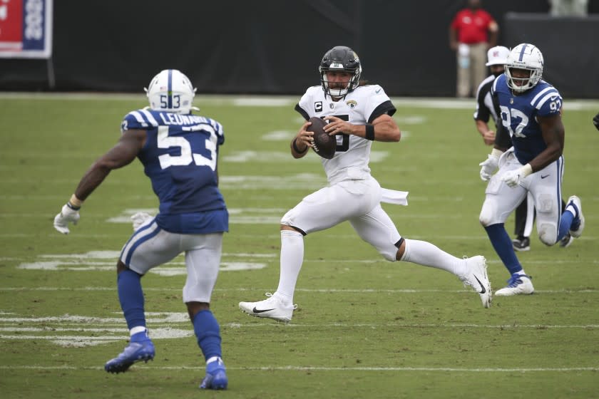 Jacksonville Jaguars quarterback Gardner Minshew, center, scrambles for yardage between Indianapolis Colts outside linebacker Darius Leonard (53) and defensive tackle Kameron Cline, right, during the second half of an NFL football game, Sunday, Sept. 13, 2020, in Jacksonville, Fla. (AP Photo/Stephen B. Morton)