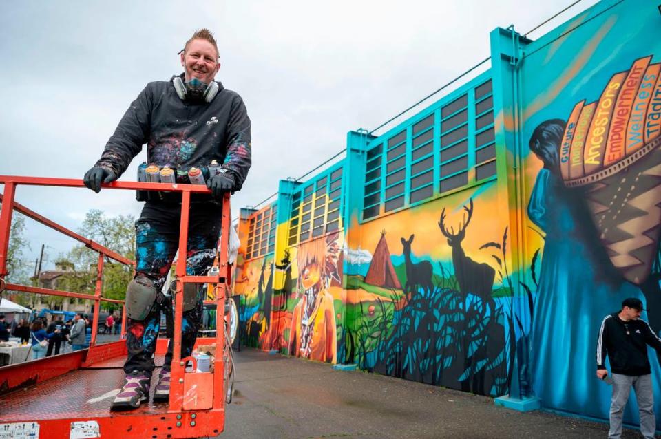 Artist Shane Grammer stands on a lift Saturday after adding some final touches to a mural that celebrates the historic name change of Sutter Middle School to Miwok Middle School. His nonprofit organization, Hope Through Art, partnered with youth artists in the Native Dads Network’s youth leadership development program and the Sacramento City Unified School District to create the mural at the school. Lezlie Sterling/lsterling@sacbee.com