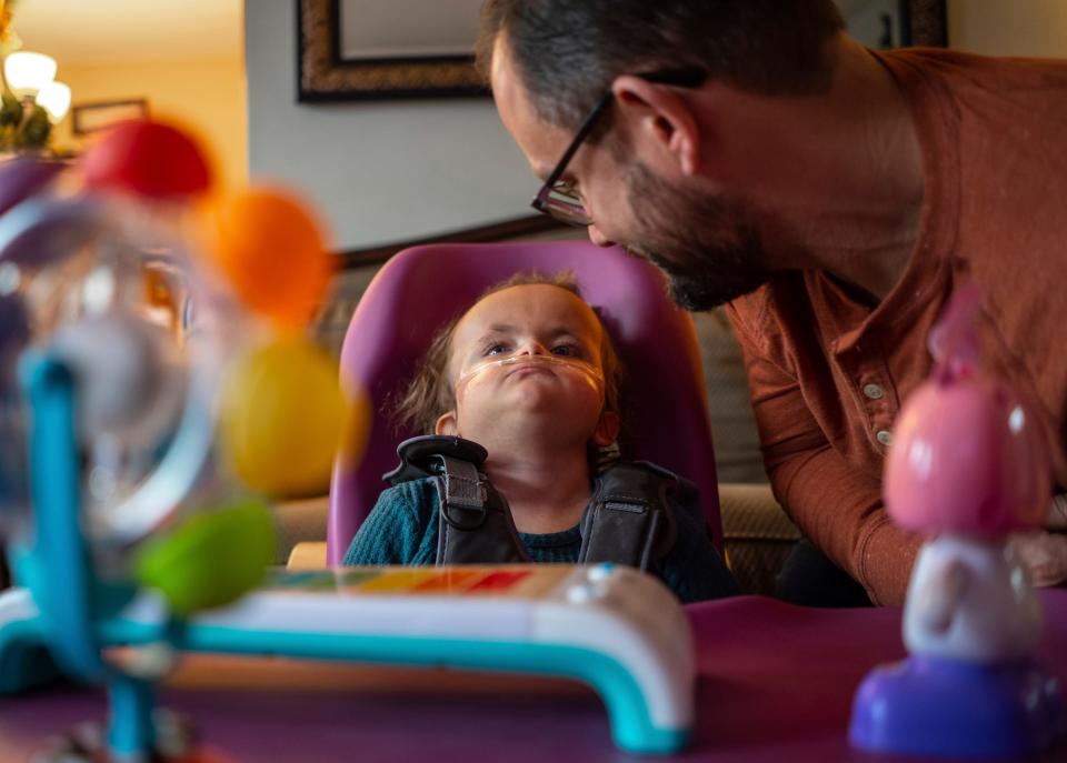 Phil Calleja, of Livonia, sits with his daughter, CC Calleja, 4, in the living room at their home on Dec. 22, 2023. CC was born with Trisomy 18, and despite intense pressure to terminate the pregnancy, the Callejas say CC is now 4 years old and a valued and interactive member of the family.