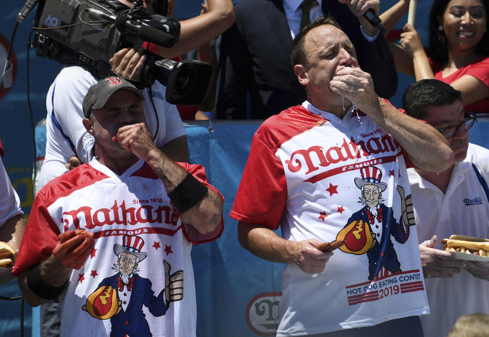 Geoffrey Esper, left, and Joey Chestnut, right, compete during the men's competition of Nathan's Famous July Fourth hot dog eating contest, Thursday, July 4, 2019, in New York's Coney Island. (AP Photo/Sarah Stier)