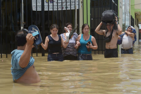 Residents cross a flooded street after rivers breached their banks due to torrential rains, causing flooding and widespread destruction in Piura, Peru, March 27, 2017. REUTERS/Miguel Arreategui