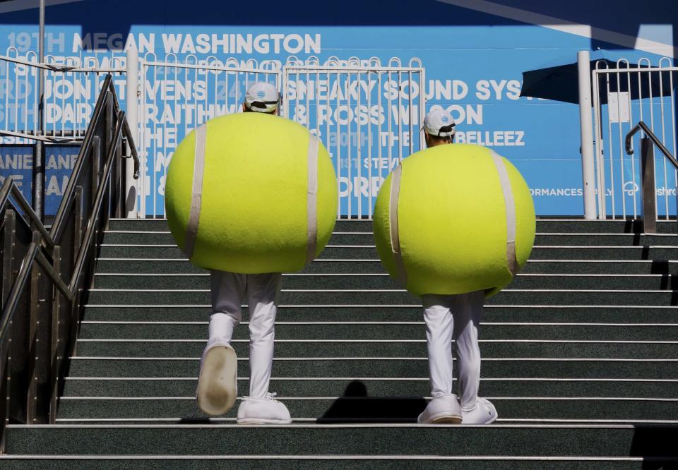 Entertainers dressed in outfits shaped like tennis balls walk around the Rod Laver Arena at the Australian Open 2015 tennis tournament in Melbourne January 21, 2015. REUTERS/Thomas Peter (AUSTRALIA - Tags: SPORT TENNIS)