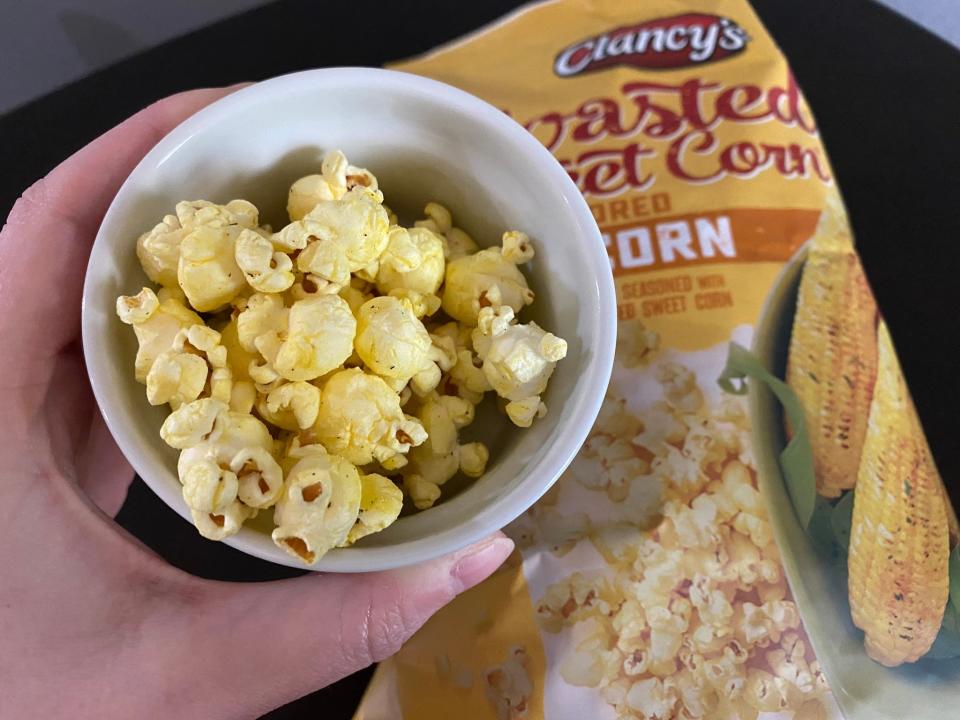 The writer holds a cup of Clancy's sweet-corn popcorn with bag in background