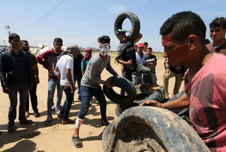 Palestinian demonstrators prepare tires to be burnt during a tent city protest at the Israel-Gaza border, in the southern Gaza Strip April 2, 2018. REUTERS/Ibraheem Abu Mustafa